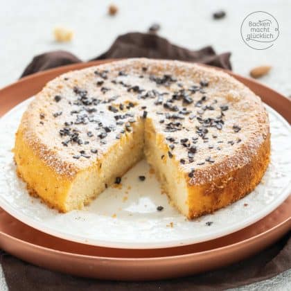 Angeschnittener Marzipankuchen mit Puderzucker und Schokostreuseln auf weißem Teller