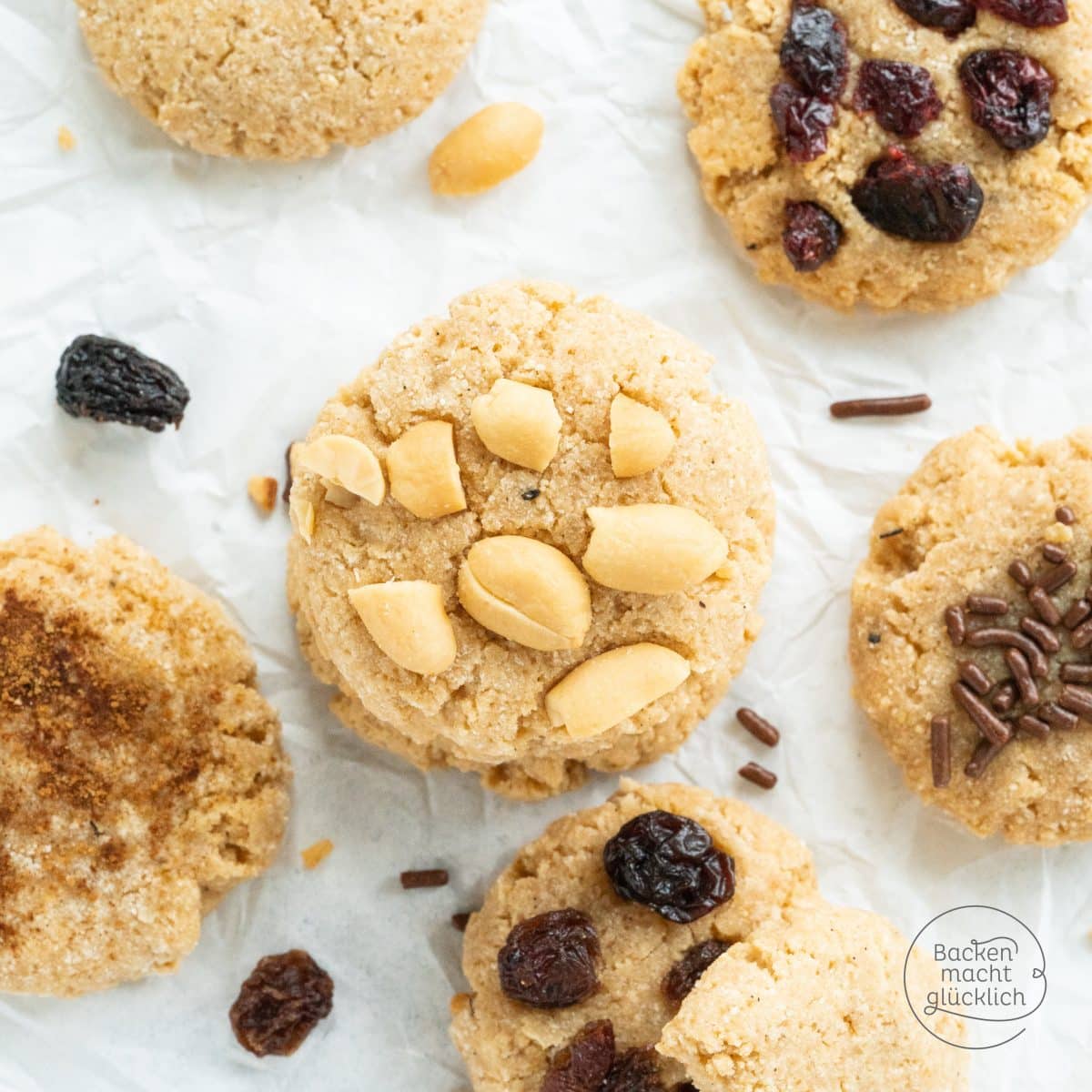 Protein-Cookies mit Erdnüssen, Rosinen, Streuseln und Zimt auf Backpapier
