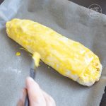 Ungebackener Strudel wird auf Backpapier mit Eigelb bestrichen