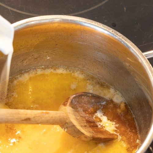 Sahne wird in geschmolzenen Zucker für Karamell gegossen, Kochtopf mit Holzlöffel