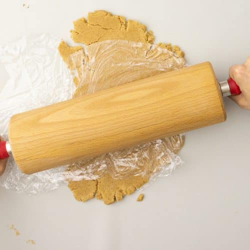 Spekulatiusteig zwischen Frischhaltefolie mit Nudelholz ausrollen