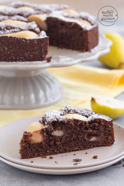 Angeschnittener Schoko-Birnenkuchen mit Puderzucker, Stück auf Teller vor Kuchenplatte