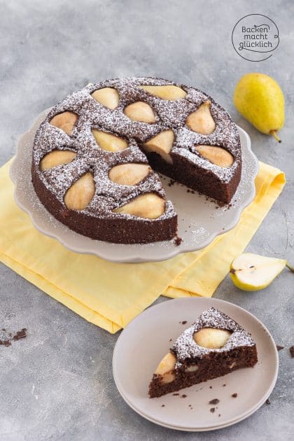Angeschnittener Schoko-Birnenkuchen mit Puderzucker, Stück auf Teller daneben