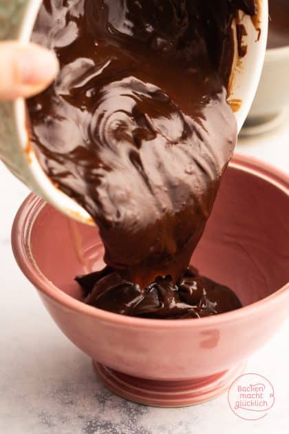 Geschmolzene Schokoladen-Ganache wird in rosa Rührschüssel gegossen