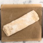 Gerollter Handbrotteig auf Backpapier vor dem Backen im Blech
