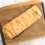 Gefülltes Handbrot mit Käse und Schinken, eingeschnitten auf Backpapier