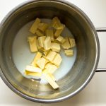 Butterwürfel und Milch im Kochtopf für Pistaziencreme