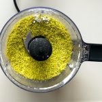 Fein gemahlene Pistazien im Küchenmaschinenbehälter vor dem Vermischen