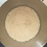 Aufgegangener Hefeteig mit Blasen in Edelstahlschüssel für Wurzelbrot