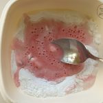 Rosa Mochi-Teig wird mit Löffel in Schüssel mit Reismehl verrührt