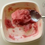 Löffel hebt rosa Mochi-Teig aus weißer Schüssel