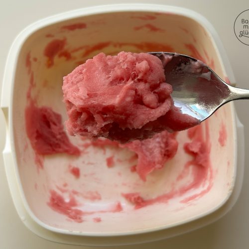 Löffel hebt rosa Mochi-Teig aus weißer Schüssel