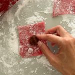 Hand platziert braune Füllung auf rosa Mochiteig-Quadrat