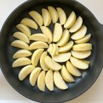 Apfelspalten kreisförmig angeordnet in schwarzer Pfanne für Tarte Tatin