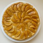 Tarte Tatin mit karamellisierten Apfelspalten kreisfoermig auf weissem Teller