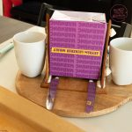 Lebkuchenhaus wird mit Karton zwischen zwei Tassen gestützt