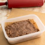 Lebkuchenteig in Frischhaltebox neben rotem Nudelholz auf Backpapier