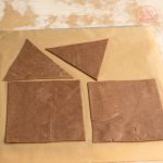 Ausgeschnittene Lebkuchenteig-Wände und Dachdreiecke auf Backpapier