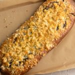 Mohnstriezel mit Streuseln auf Backpapier im Blech, Mohnfüllung sichtbar