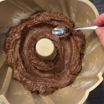 Schokoladenteig wird mit Löffel in Gugelhupfform glattgestrichen