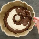Heller und dunkler Rührteig wird schichtweise in eine Gugelhupfform gelöffelt