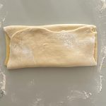Gefaltetes Hefeteigpäckchen für Splitterbrötchen auf bemehlter Arbeitsfläche