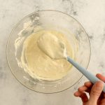 Glatter Macarons-Teig wird in Glasschüssel mit Silikonspatel verrührt