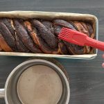Schokoladen-Babka in Kastenform wird mit Zuckersirup bepinselt