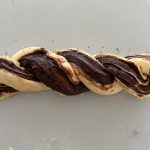 Geflochtener Babka-Teigstrang mit Schokoladenfüllung auf Arbeitsfläche vor dem Backen