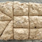 Bemehlter Brötchenteig in gleichmäßige Quadrate geschnitten auf Backmatte
