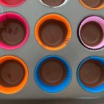 Erdnussbutter-Cups in bunten Silikonförmchen im Muffinblech, Schokolade fest