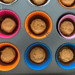Erdnussbutter-Teigportionen in bunten Silikonförmchen im Muffinblech