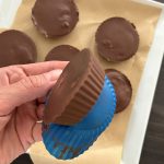 Peanut-Butter-Cup wird aus blauer Silikonform gelöst, weitere auf Backpapier