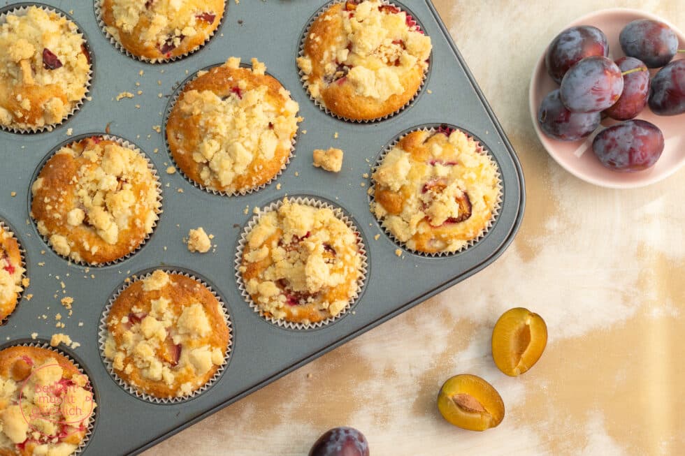Zwetschgenmuffins mit Streuseln auf einem Muffinblech